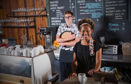 Personal de una cafetería atendiendo detrás del mostrador junto a la máquina de café